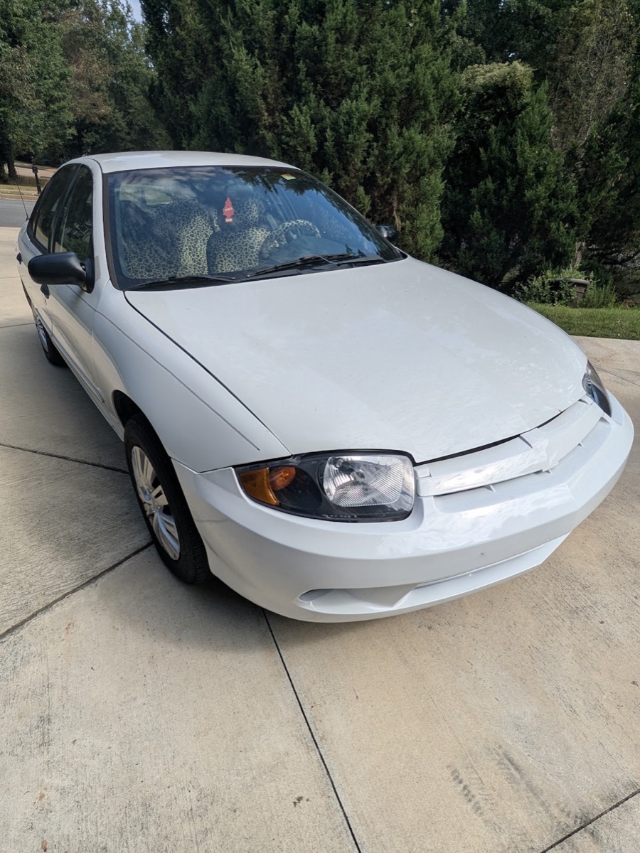A white sedan with a smooth, glossy repainted hood and restored clear headlights, finished at Ultimate Auto Body Shop